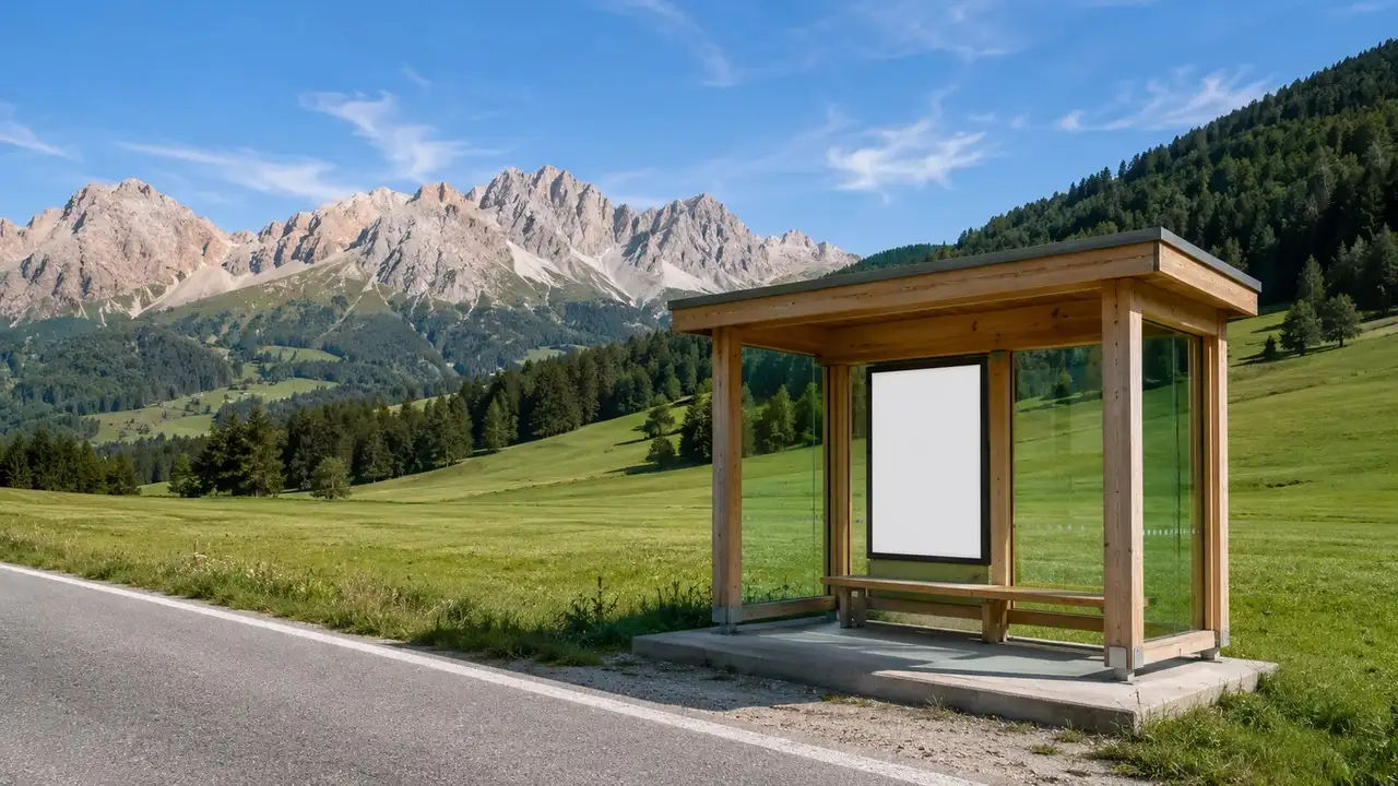 Zastávka regionálního autobusu u silnice v Pustertalu s dolomitskými štíty na obzoru