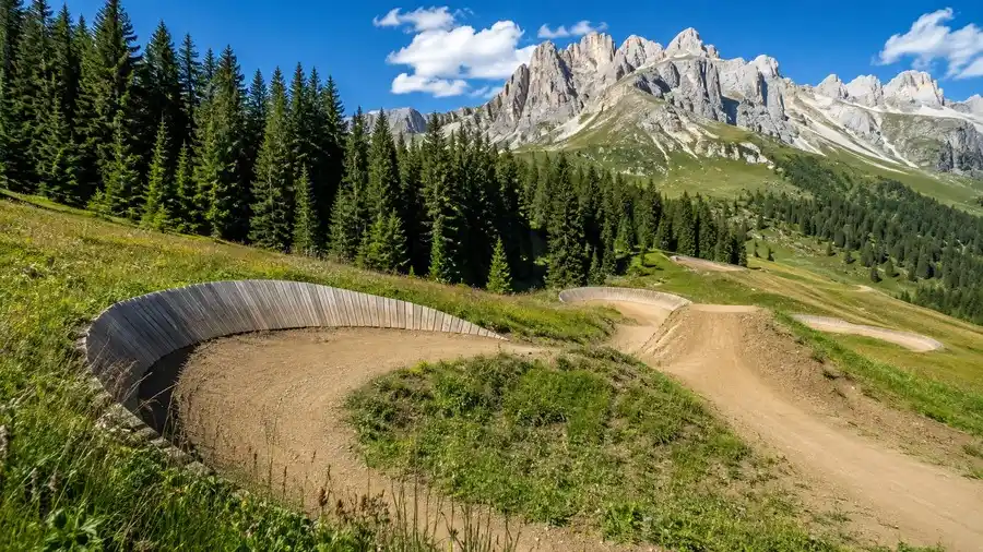 Flow trail bike parku na Kronplatzu vedoucí horskou loukou pod dolomitským hřebenem