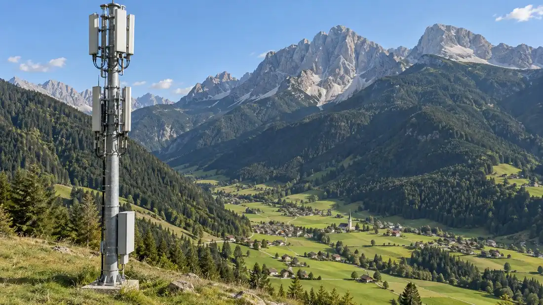 Telekomunikační vysílač na zalesněném svahu nad horskou vesnicí v Jižním Tyrolsku