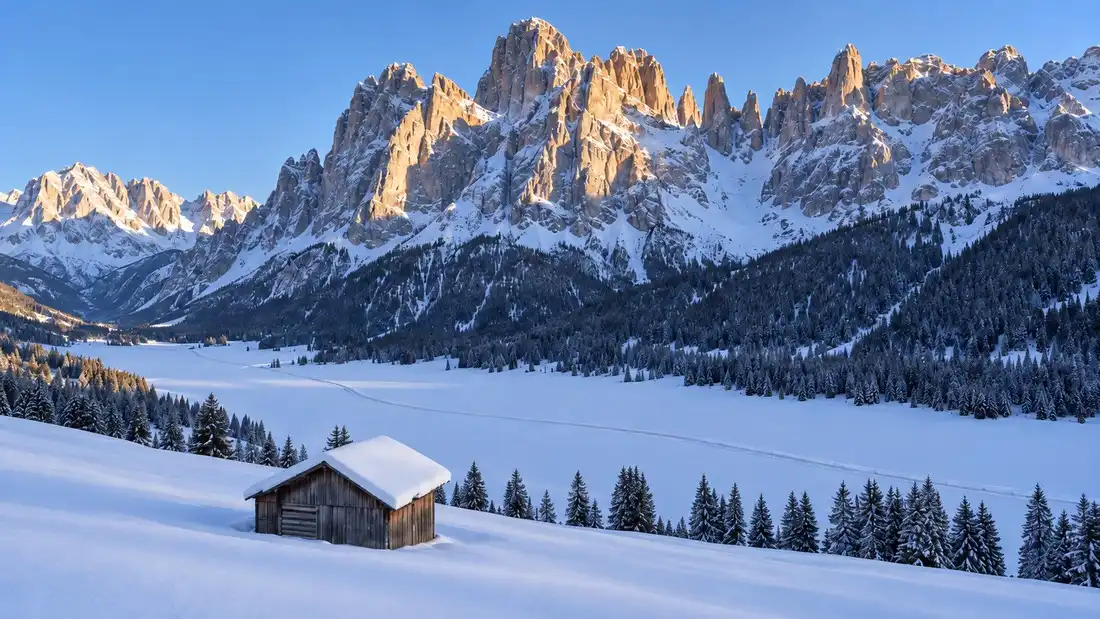 Zasněžené dno údolí pod stěnami Sextenských Dolomit, upravená zimní cesta mezi loukami